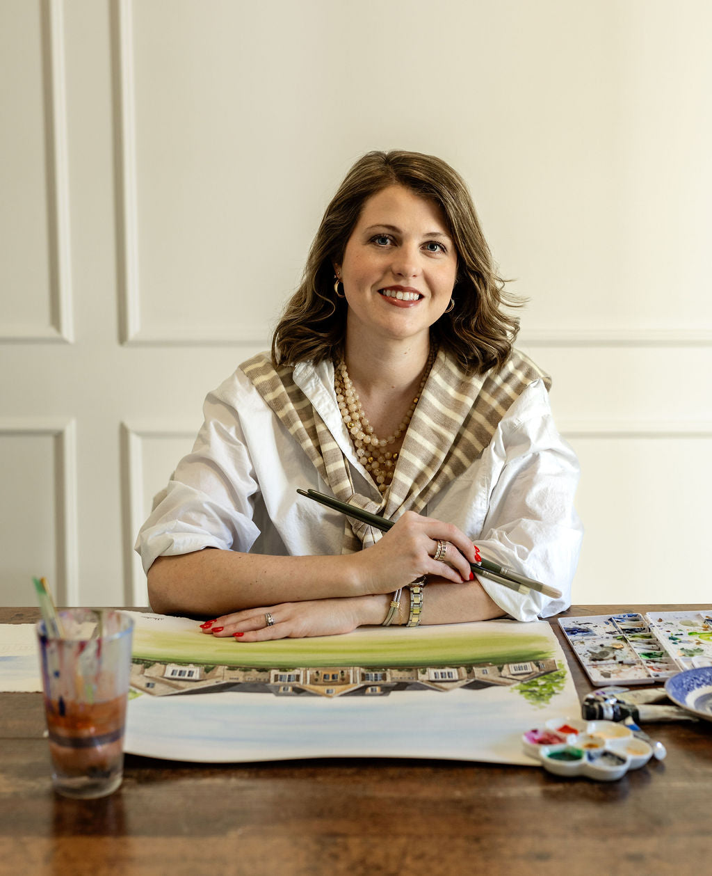 Woman sitting at a table with art supplies, smiling.